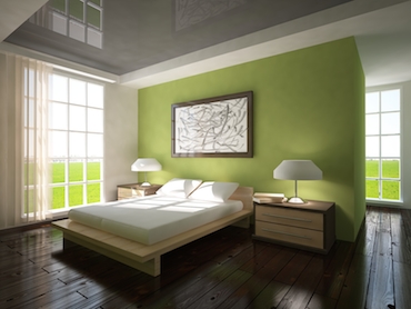  room swith a hardwood floor bright windows on two sides, and a two person bed with bedside tbale and lamp on each side